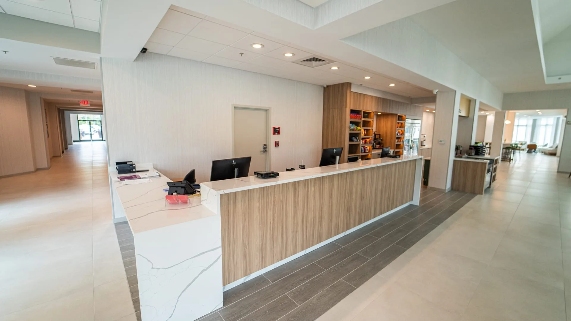 Long hotel reception desk with a wood-look front, white veined countertop and matching end panel